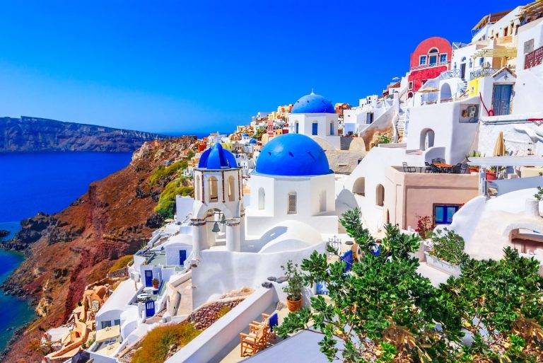 “Sunset view of white buildings and blue-domed churches in Oia, Santorini, Greece”