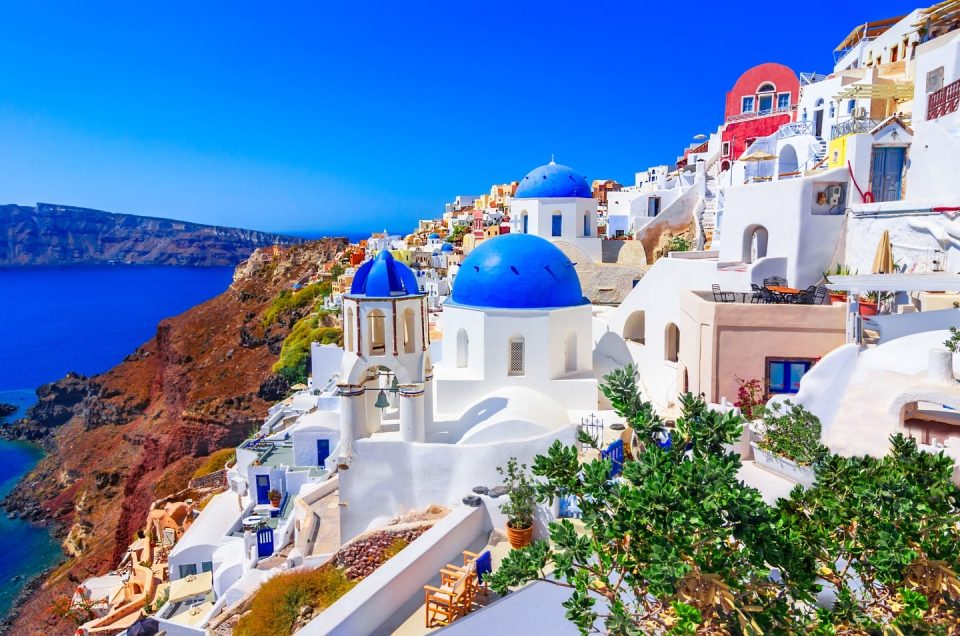 “Sunset view of white buildings and blue-domed churches in Oia, Santorini, Greece”